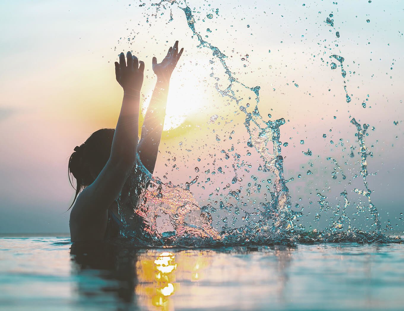 woman standing in the sea, splashing water up with her arms