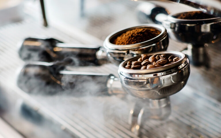 coffee grounds and beans inside two barista machine baskets