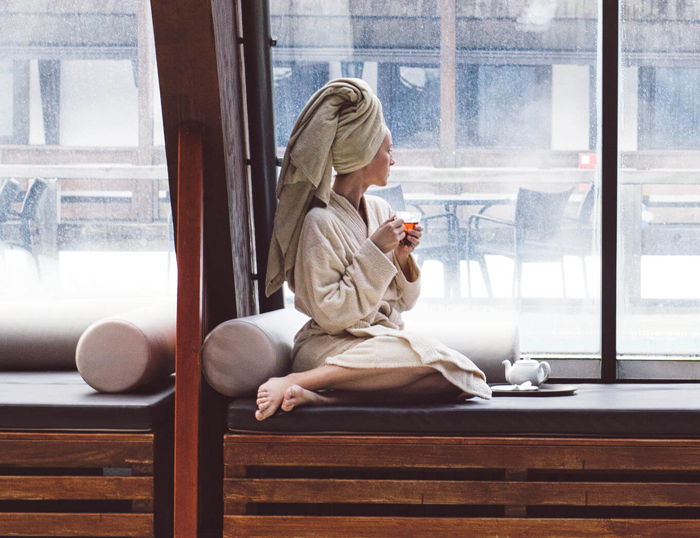 woman sitting in her dressing gown at a spa, holding a cup of tea