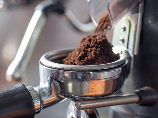coffee grinds coming out of a grinder and into a barista machine basket