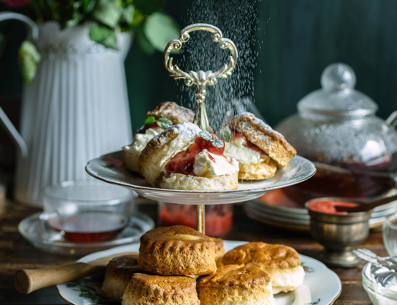 afternoon tea tray with scones and a pot of tea in the background