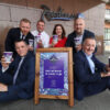 Group_of_people_sitting_around_an_outdoor_footpath sign holding takeaway coffee cups