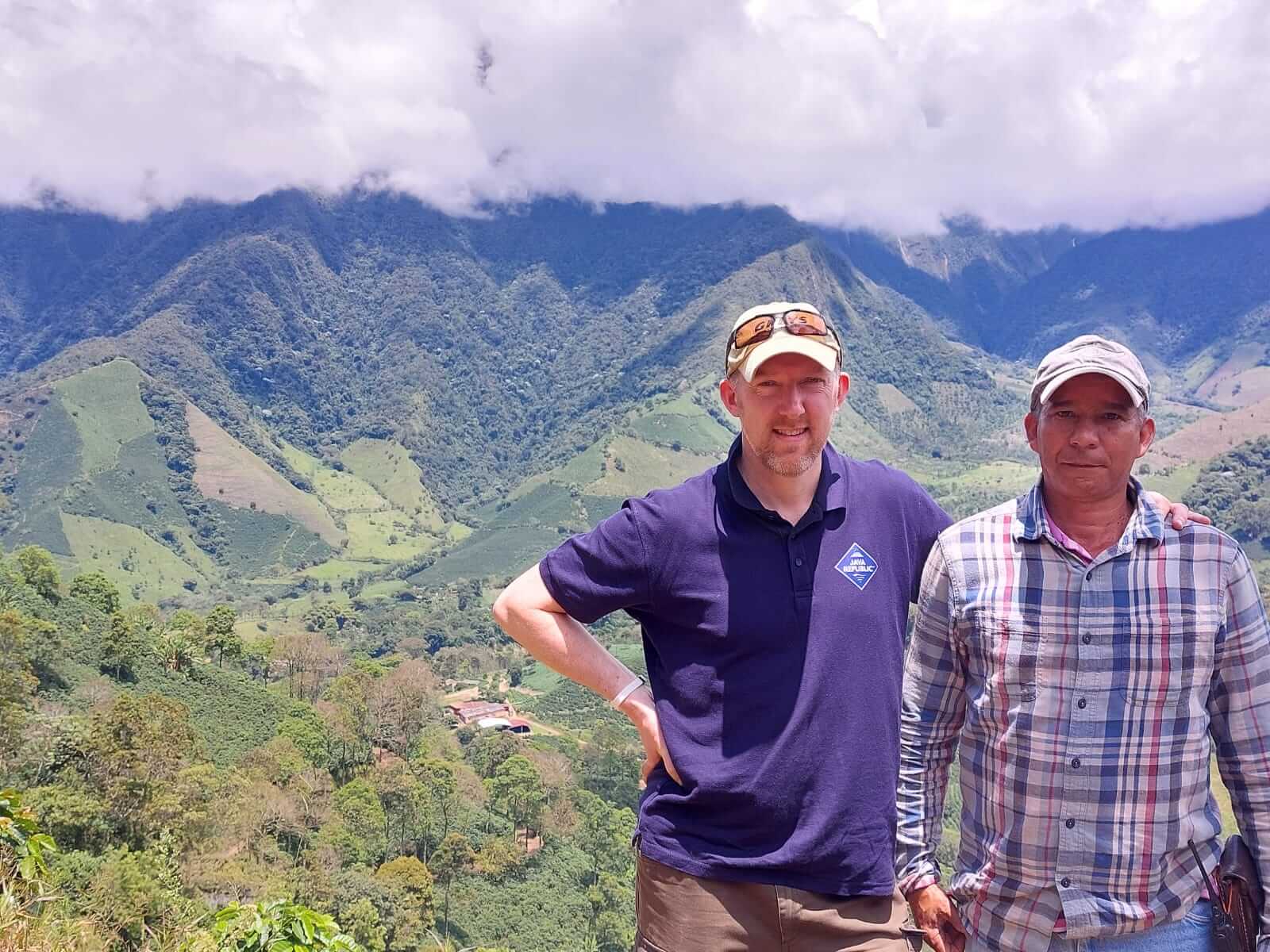 Roy Sanderson and a Colombia man smiling in front of a beautiful Colombian landscape.