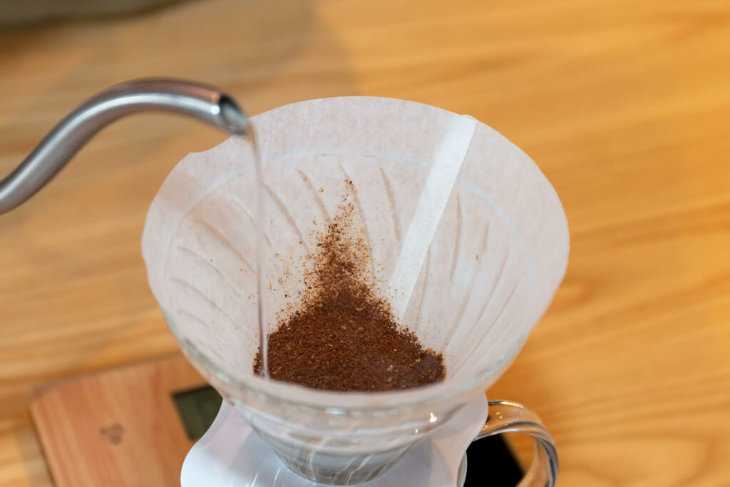 Kettling pouring hot water onto ground coffee to make filter coffee using a v60