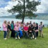 Group of people standing and sitting in front of a lake