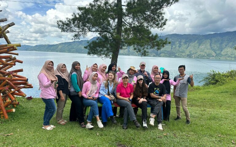 Group of people standing and sitting in front of a lake