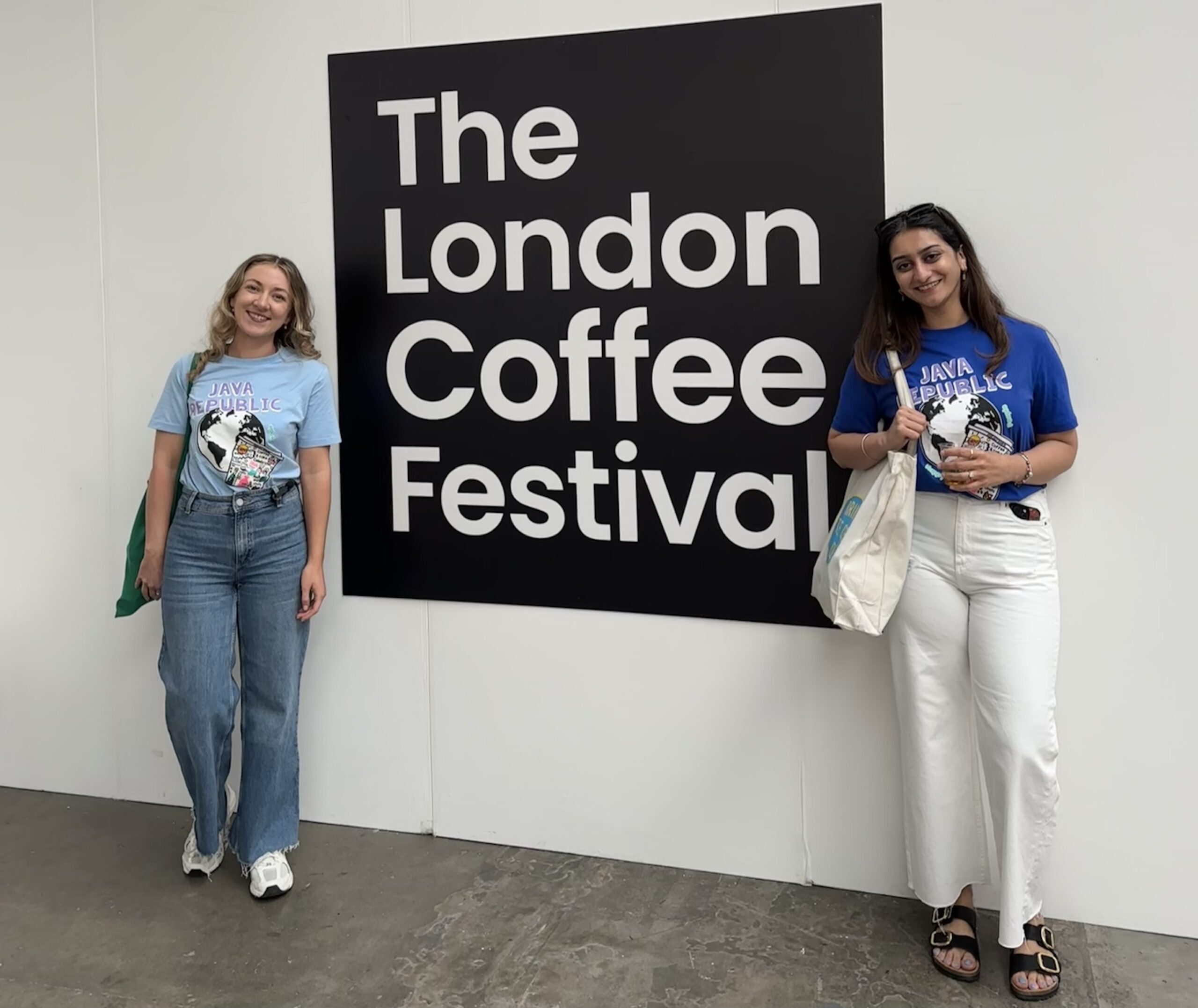 Laura McKitterick and Anushka Bedi at the London Coffee festival 2025 sign